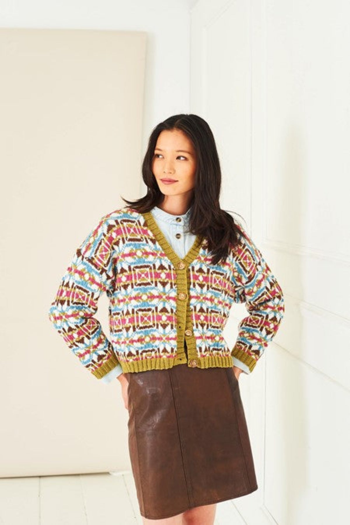 A colourful short colourwork cardigan from Stylecraft knitting pattern 10283. The cardigan is knit in Naturals Pure Wool DK yarn, using shades Raspberry, Cream, Mistletoe, Walnut, and Storm Blue, and features a geometric pattern.