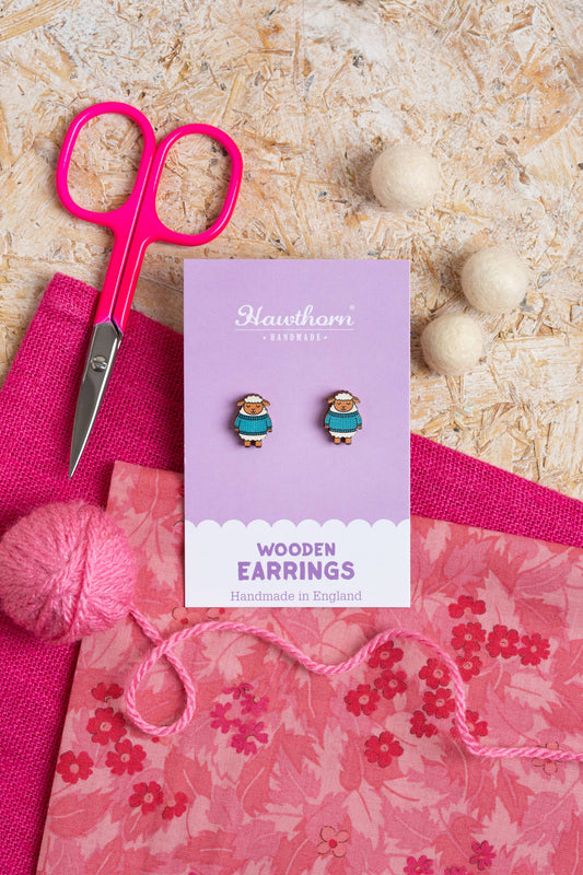 Wooden Sheep in Knitted Sweaters Stud Earrings from Hawthorn Handmade with Pink Fabric, Yarn and Scissors in background