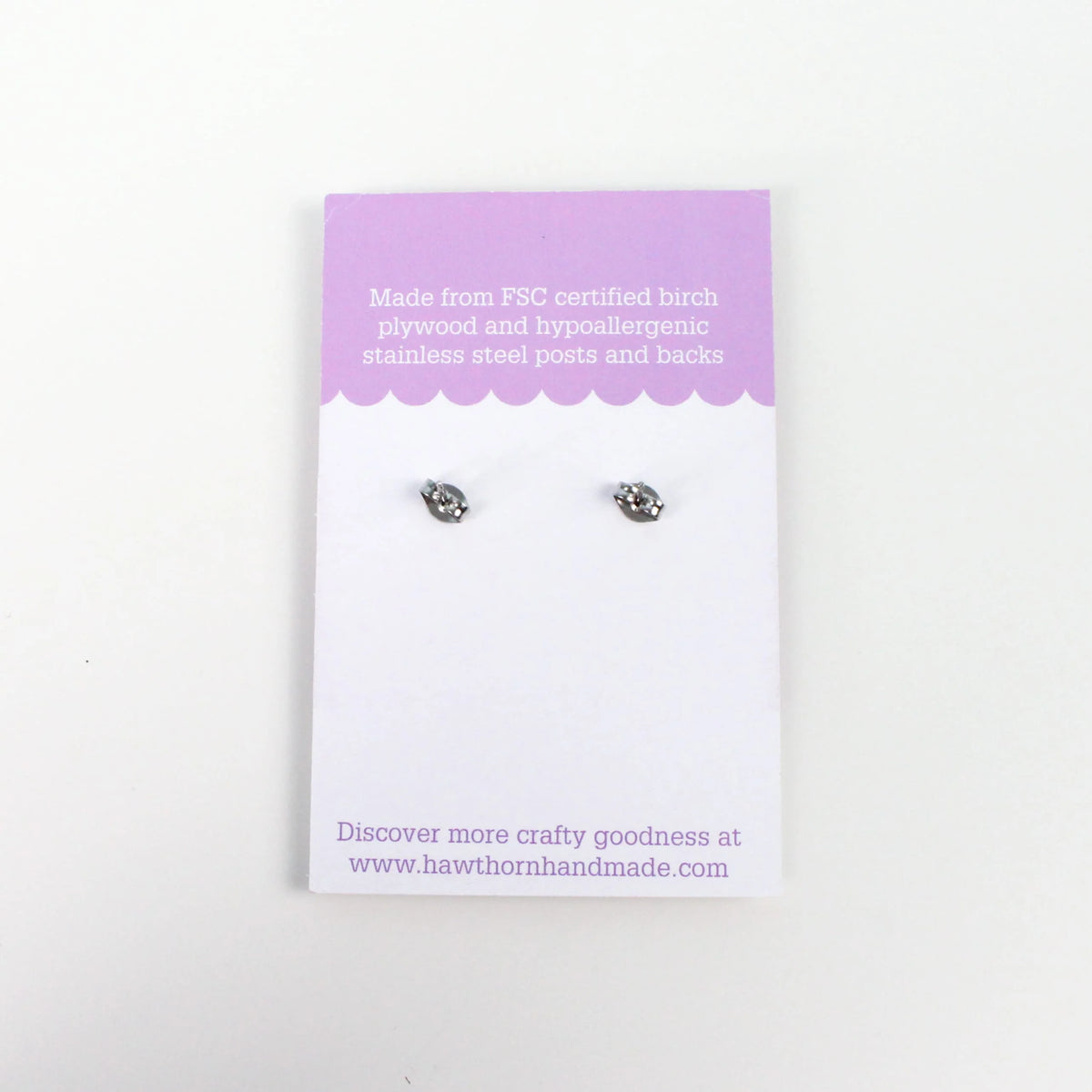 A pair of small silver stud earring backs displayed on a white and lavender backing card against a plain white background.