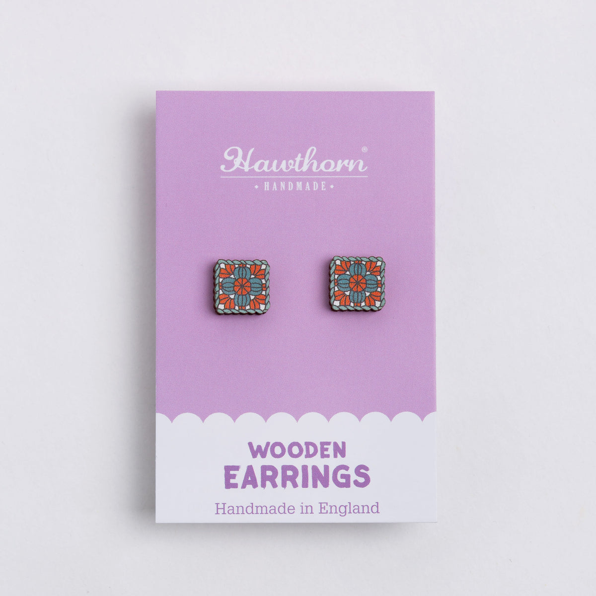 A pair of granny square wooden stud earrings, displayed on a lavender and white Hawthorn Handmade card.