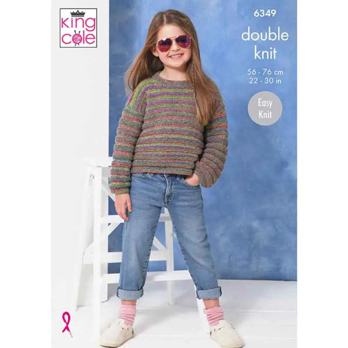 A young girl wearing a striped double-knit sweater, blue jeans, pink socks, and white shoes, standing in front of a blue backdrop. The image includes the King Cole logo and text indicating pattern number 6349, double knit, sizes 56-76 cm / 22-30 in, and Easy Knit.