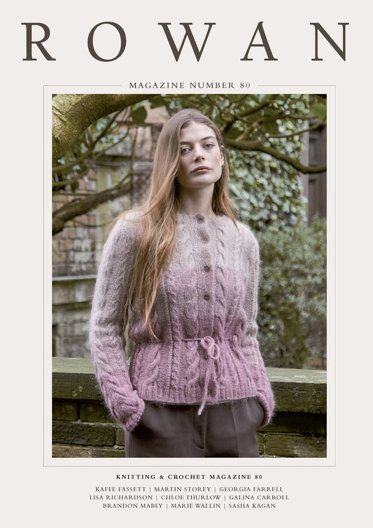 front cover of Rowan Knitting and Crochet Magazine issue 80, featuring a women wearing the Felizia cardigan in mauve, stood in front of a tree.