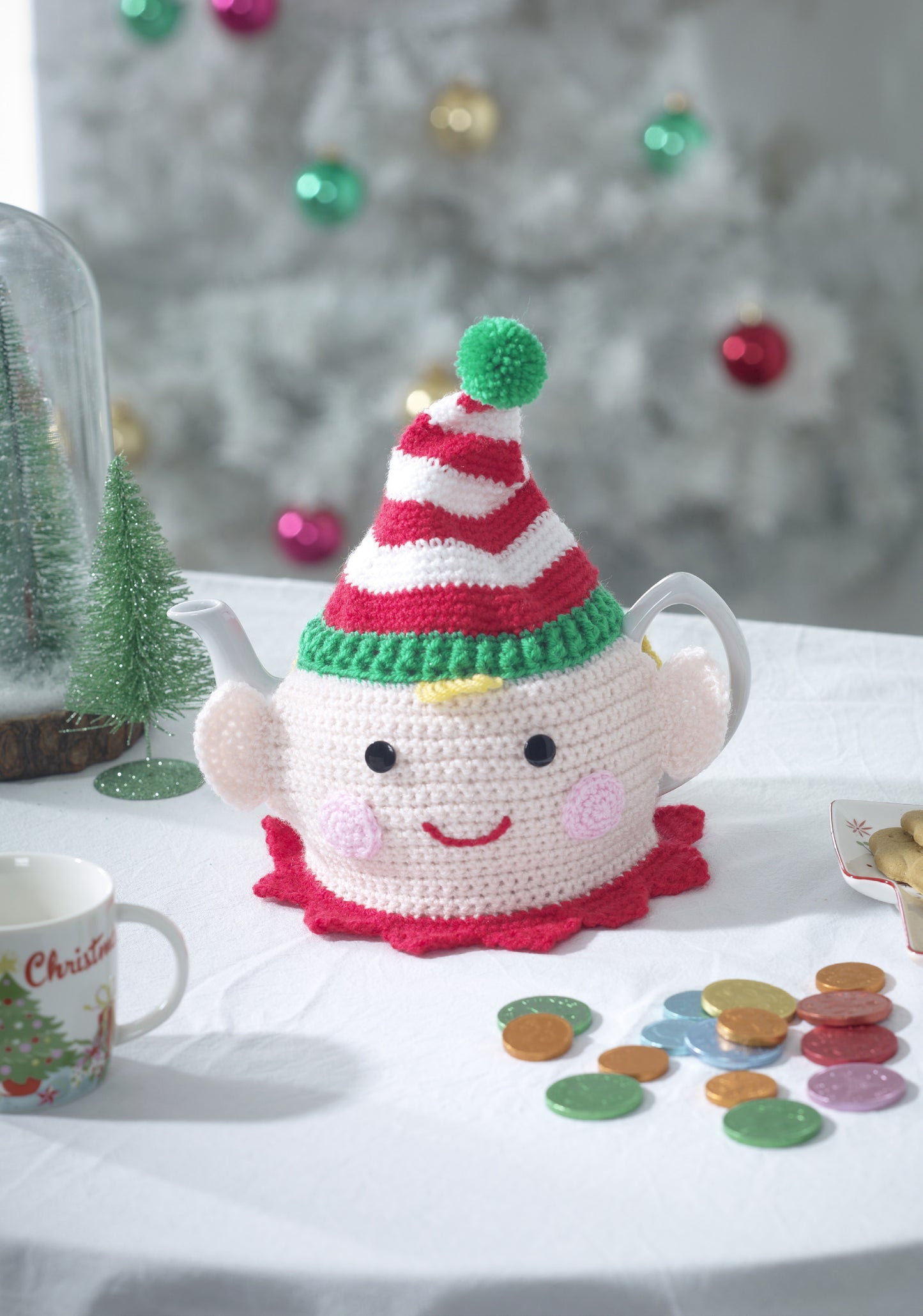 Cute little elf face tea cosy with white and red striped hat with a green bobble. This tea cosy fits a pot of 6 cups, approximately 43cm circumference x 20cm tall.
